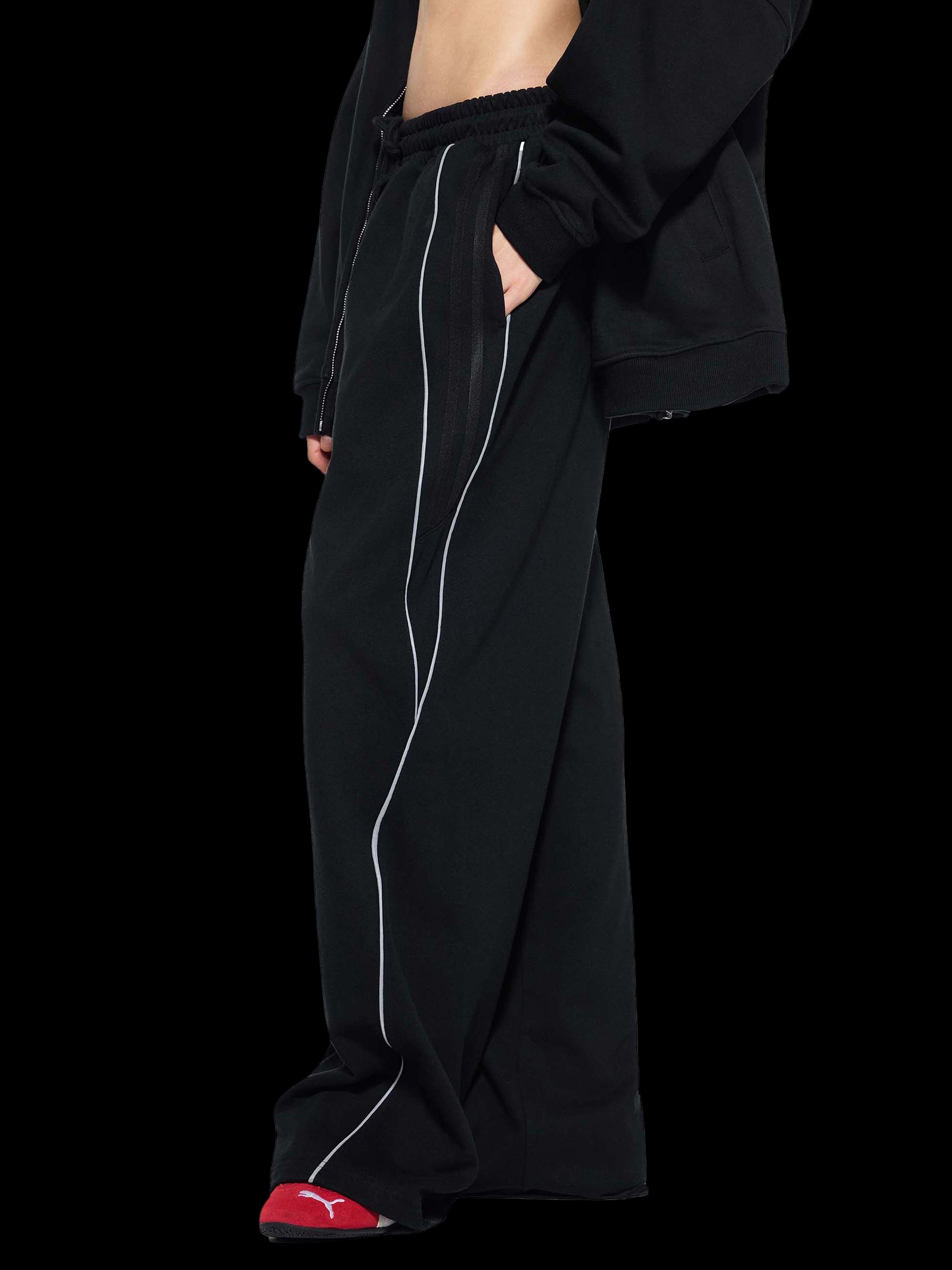 Person wearing a black outfit with white piping on a white background
