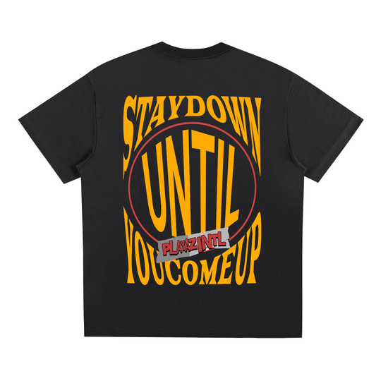 Black oversized streetwear t-shirt with bold yellow Stay Down Until You Come Up PLAYAZ INTL graphic on the back
